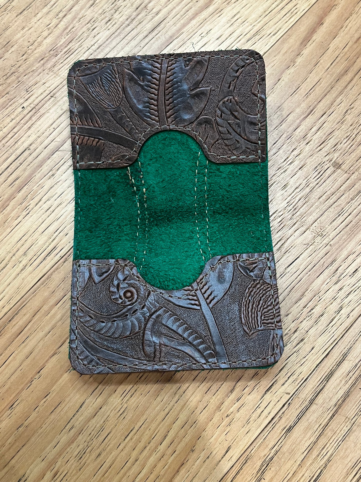 A wallet spread open showing a base color of brown leather with two card pockets in brown floral leather with brown stitching.