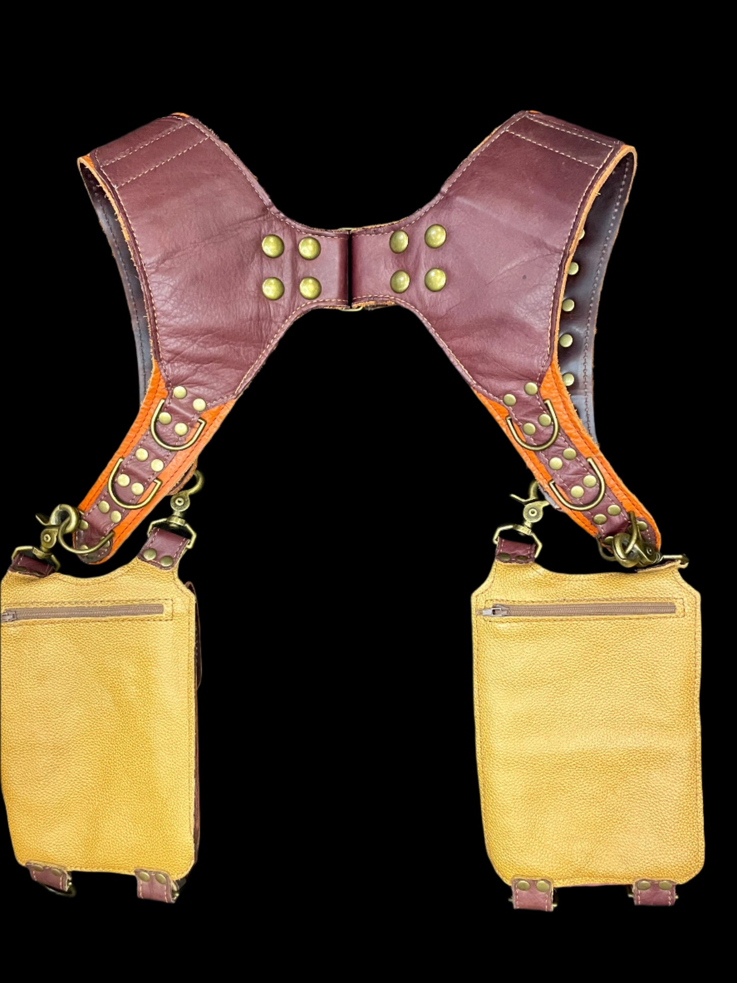 Back view of holster laid against a black background showing yellow backing and hidden zipper pockets