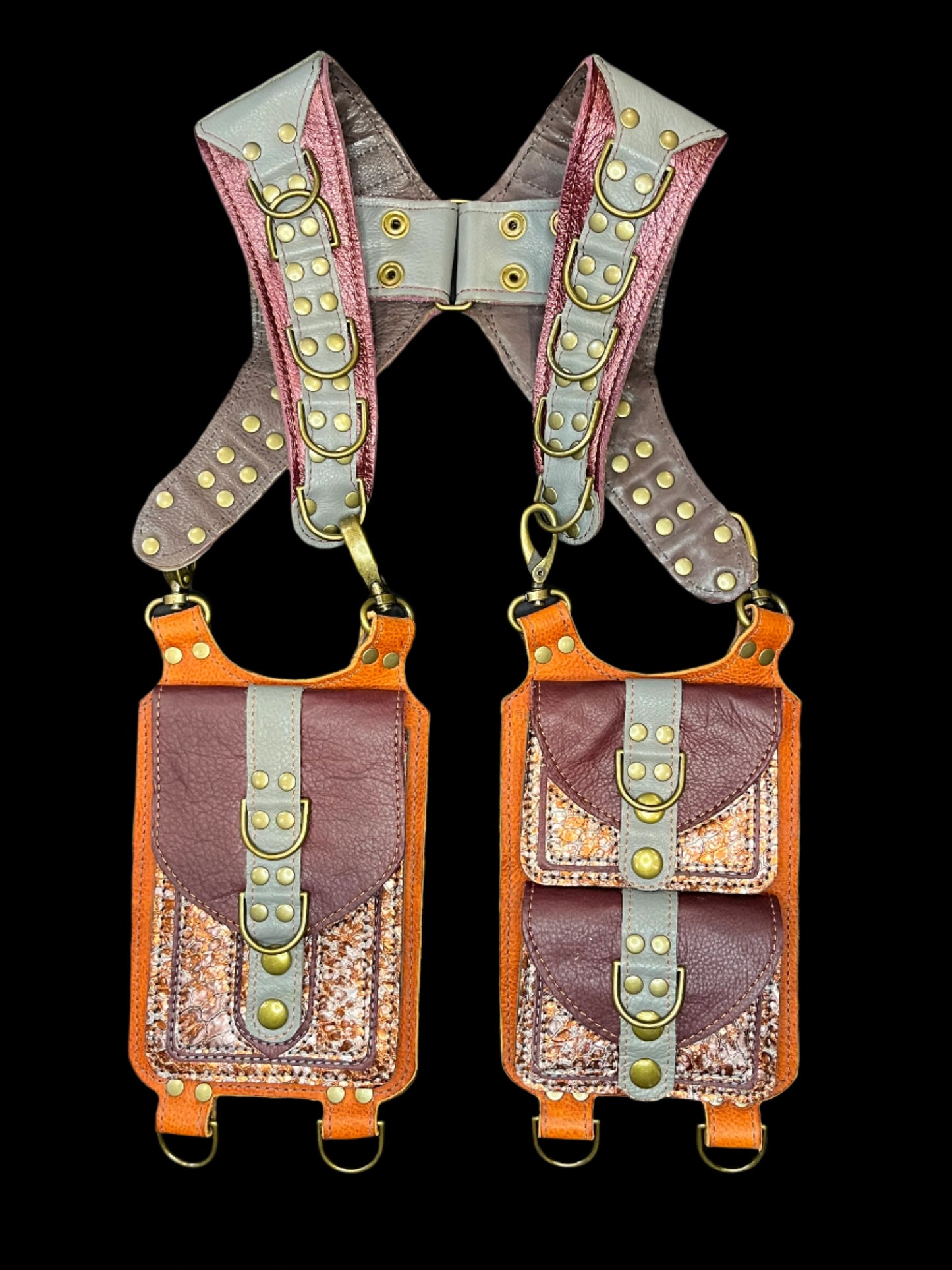 Koi holster in grey and orange leathers and antique brass hardware laid flat on a black background