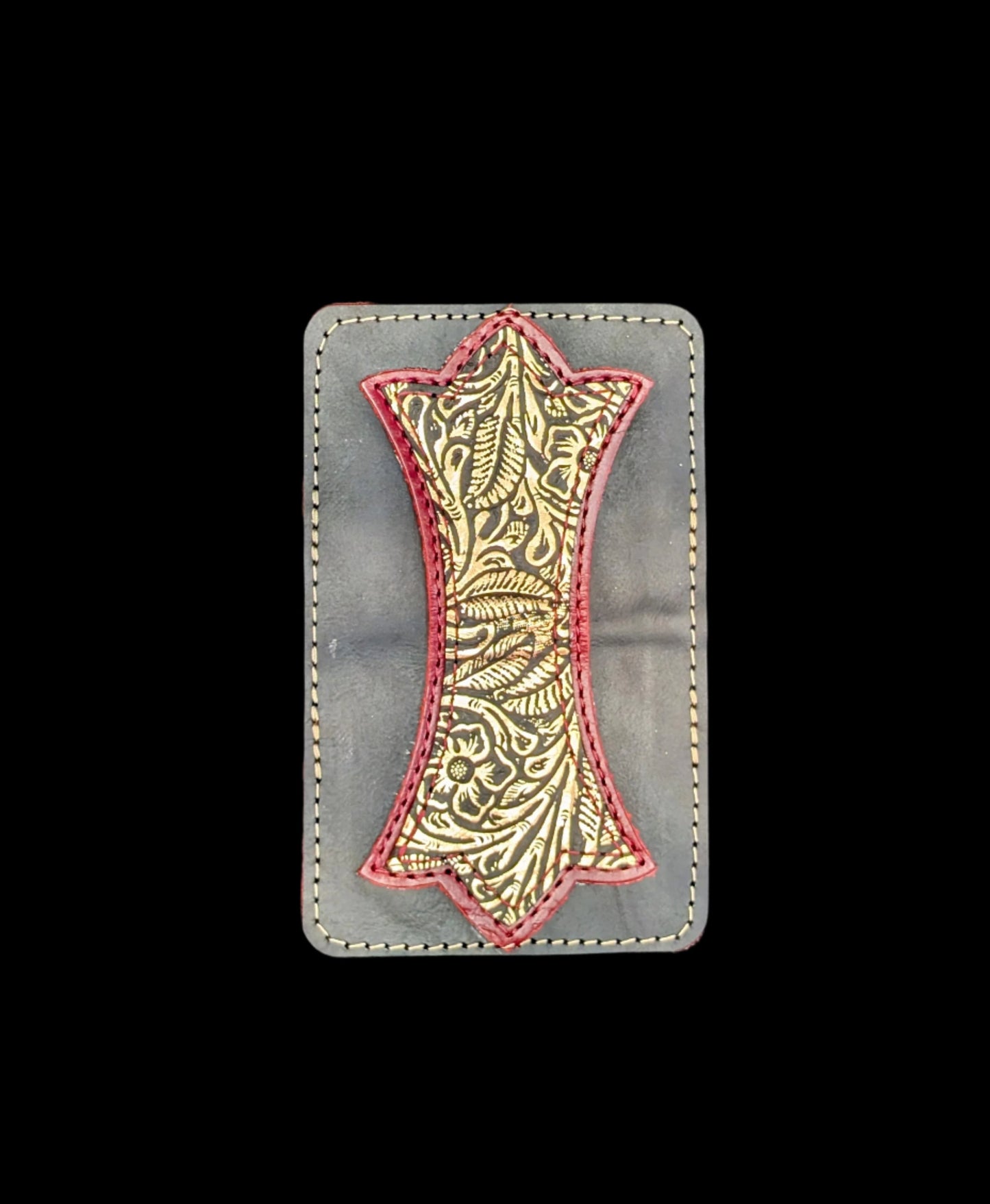 A photo of the outside of a wallet laid flat showing a base color of black leather with a layered trident accent of red leather and bronze floral leather and red and bronze stitching.