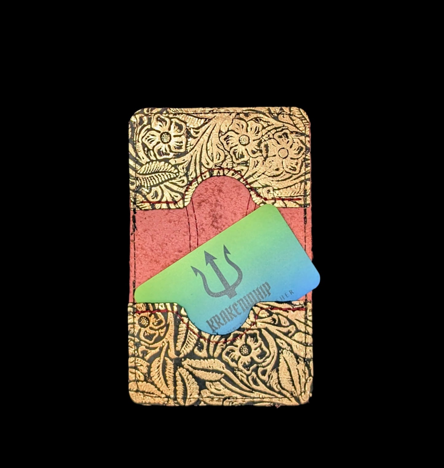 A wallet spread open showing a base color of red leather with two card pockets in bronze floral leather with red and bronze stitching. A krakenwhip business card is sticking out of one of the pockets.