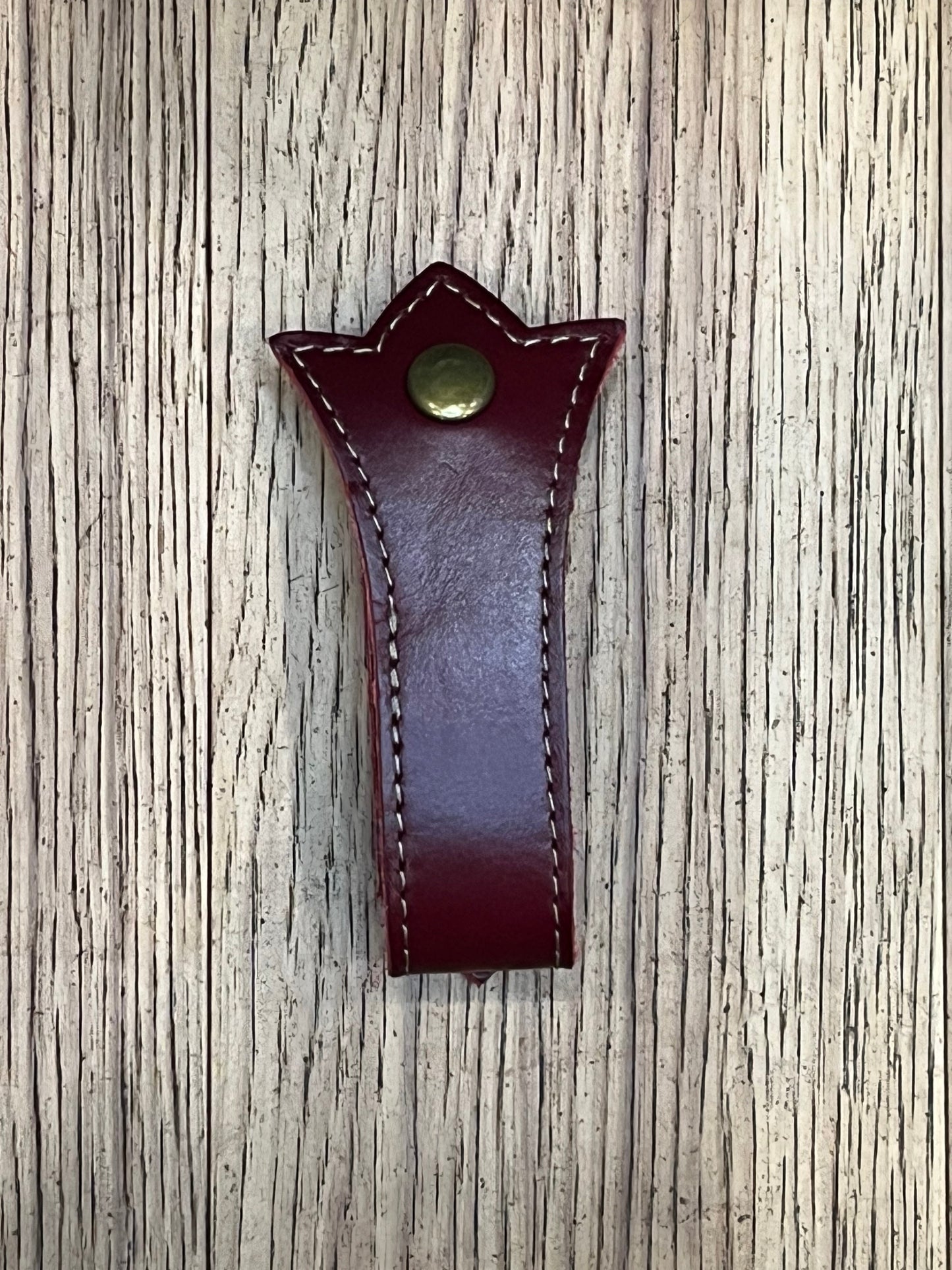 A trident shaped double layered mug frog using dark red leather, bronze stitching and a brass snap.
