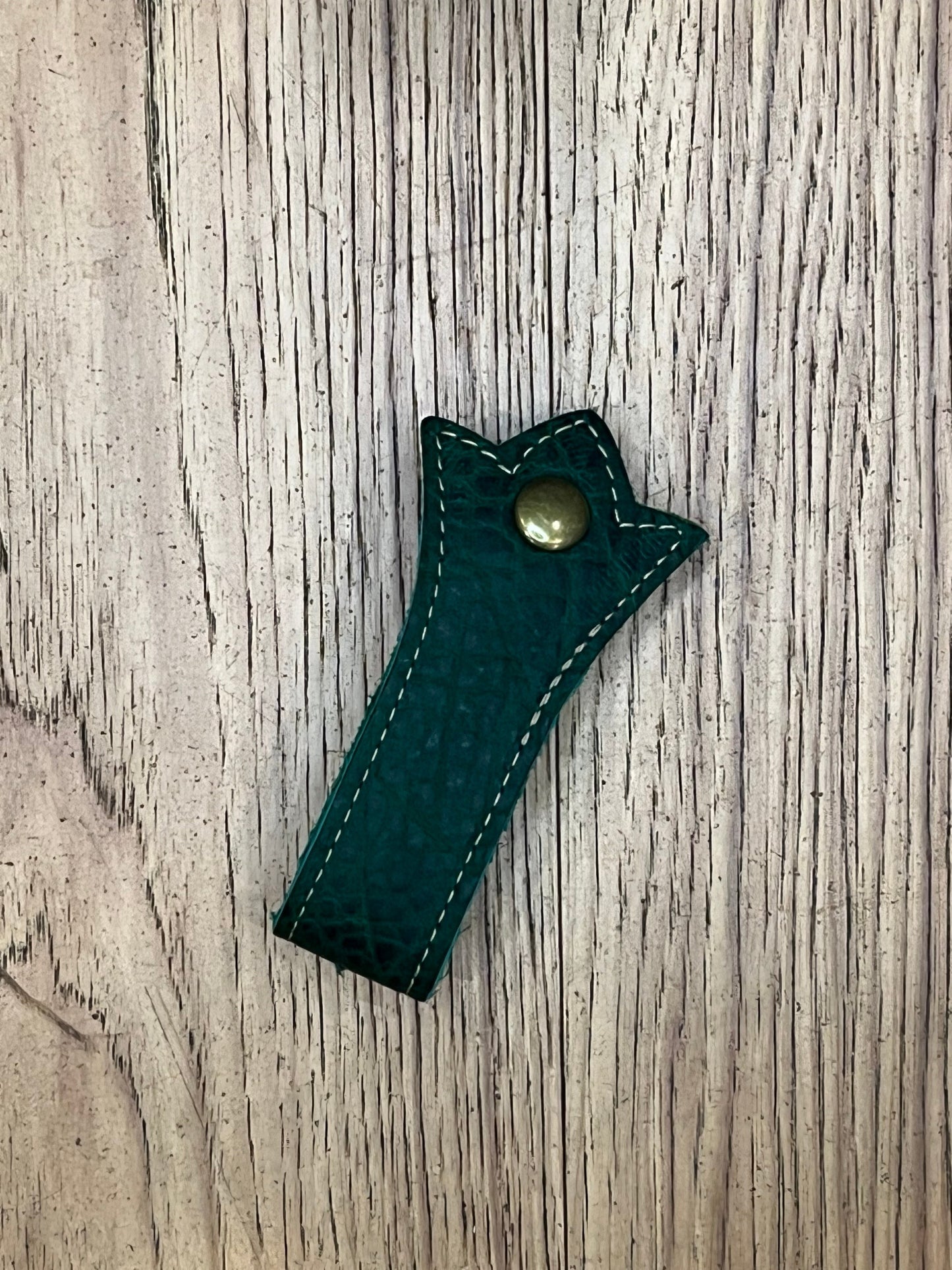 A trident shaped double layered mug frog using dark green leather, tan stitching and a brass snap.
