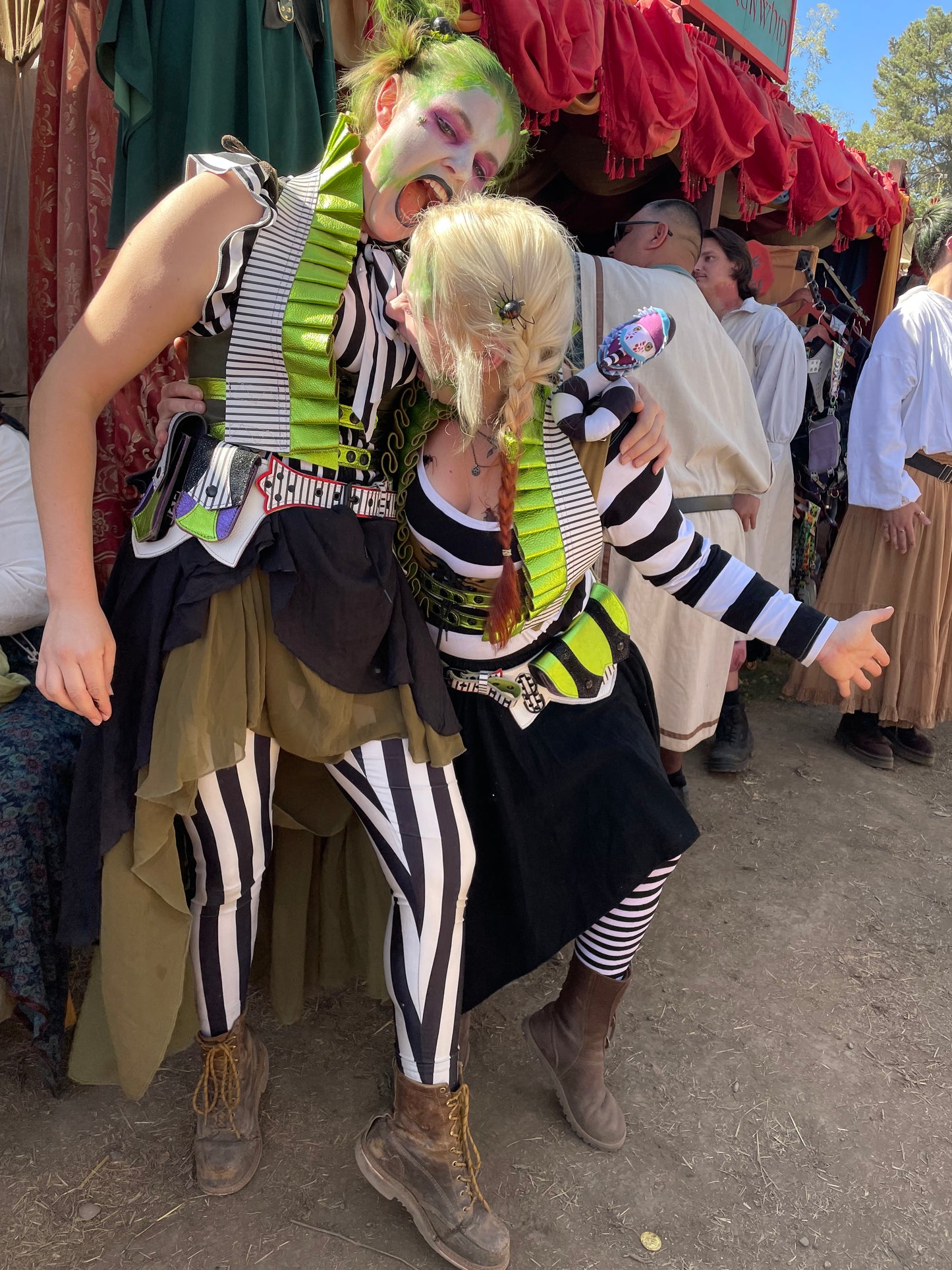 two femmes wearing showtime ruff tops and belts, each biting at eachother, wearing beetlejuice inspired costumes.