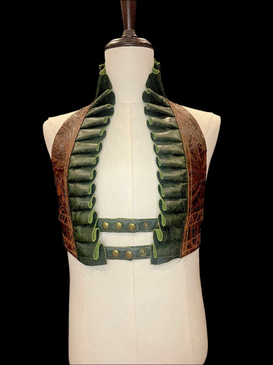 Fiddlehead frog ruff top in brown floral tooled and forest green leather with antique brass hardware on an ivory gender neutral mannequin against a black background