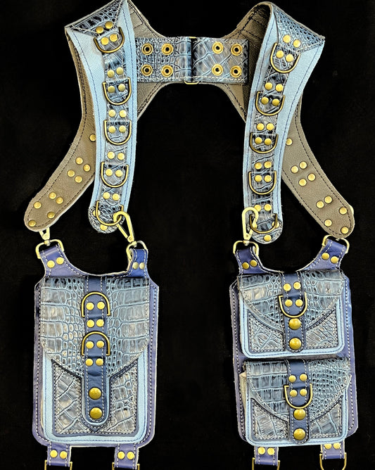 front view of blue and blue croc textured leather holster with hanging pockets and antique brass hardware