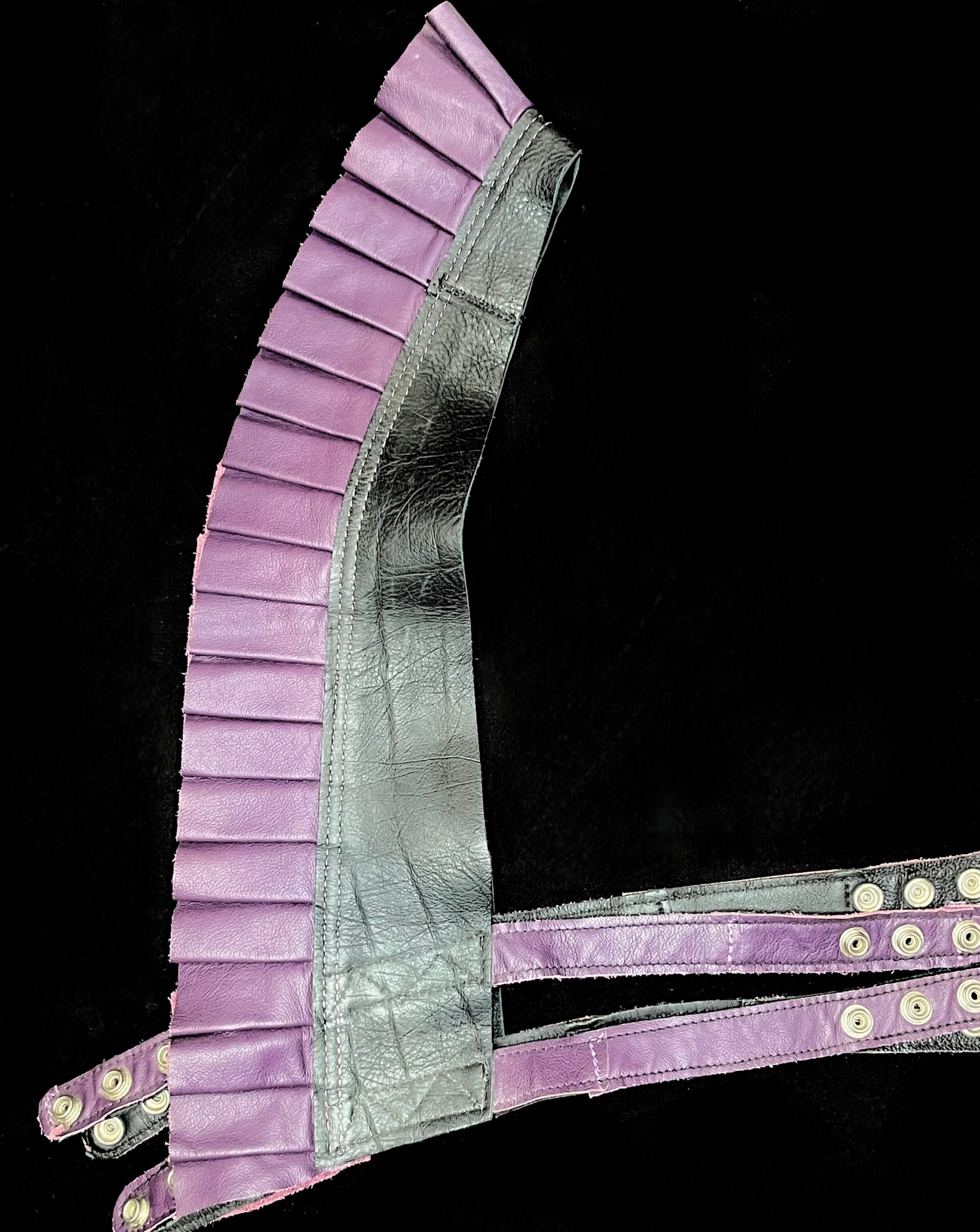 black and purple leather ruff top laid flat on its side on a black background