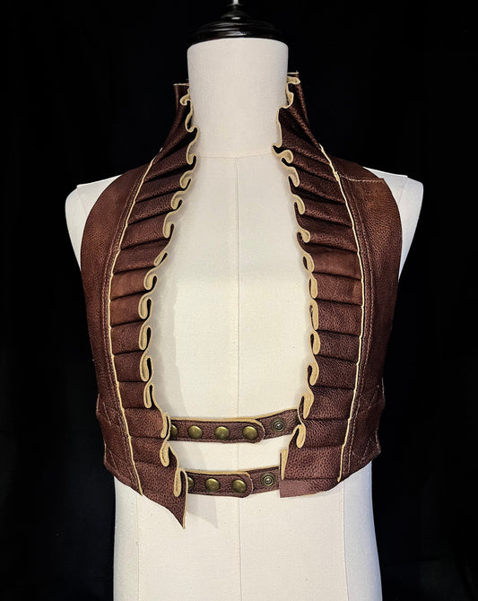 cognac brown leather ruff top with antique brass hardware on an ivory gender neutral mannequin against a black background