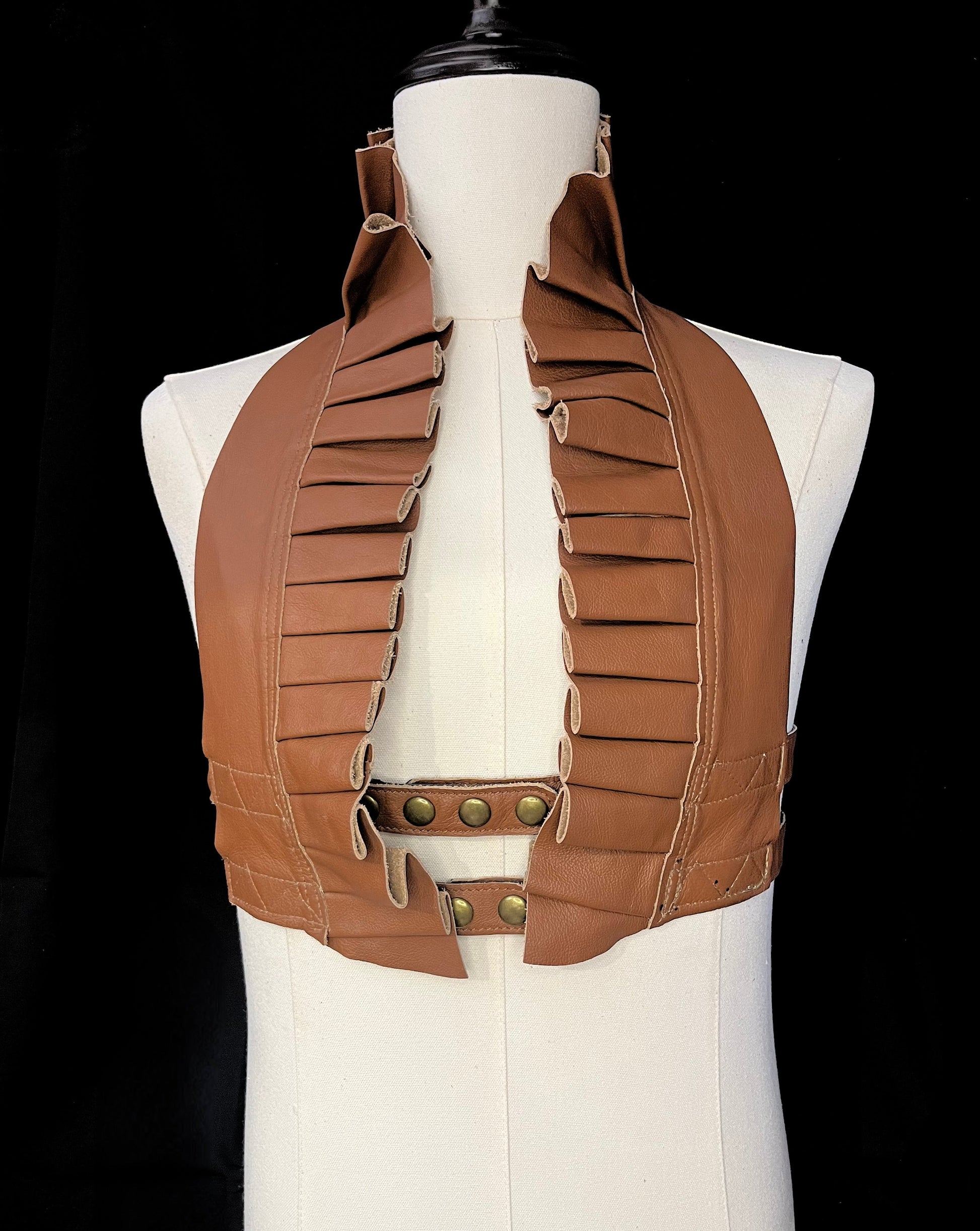 camel brown leather ruff top with antique brass hardware on an ivory gender neutral mannequin against a black background 