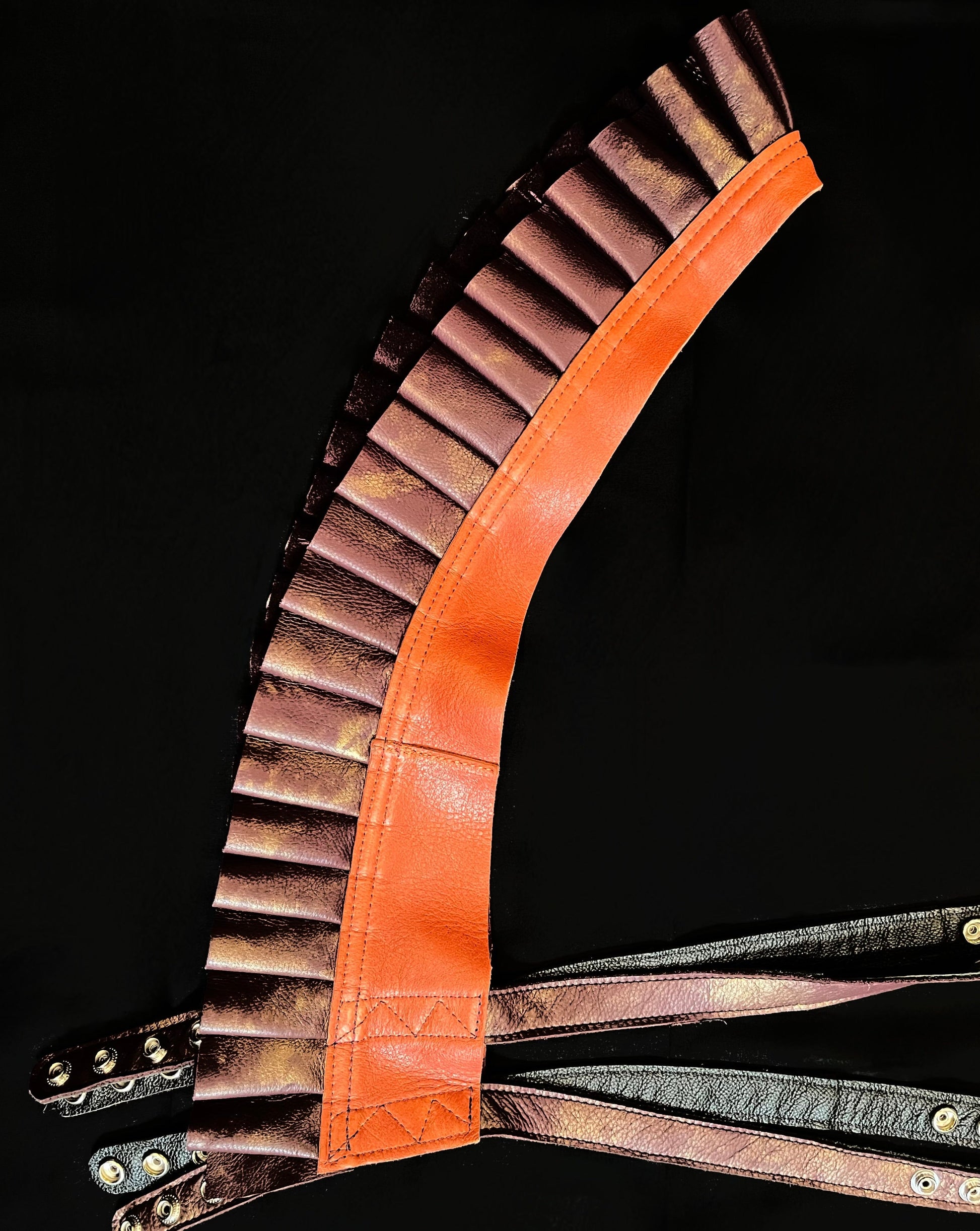 vermillion orange and distressed maroon leather ruff top laid flat on its side on a black background