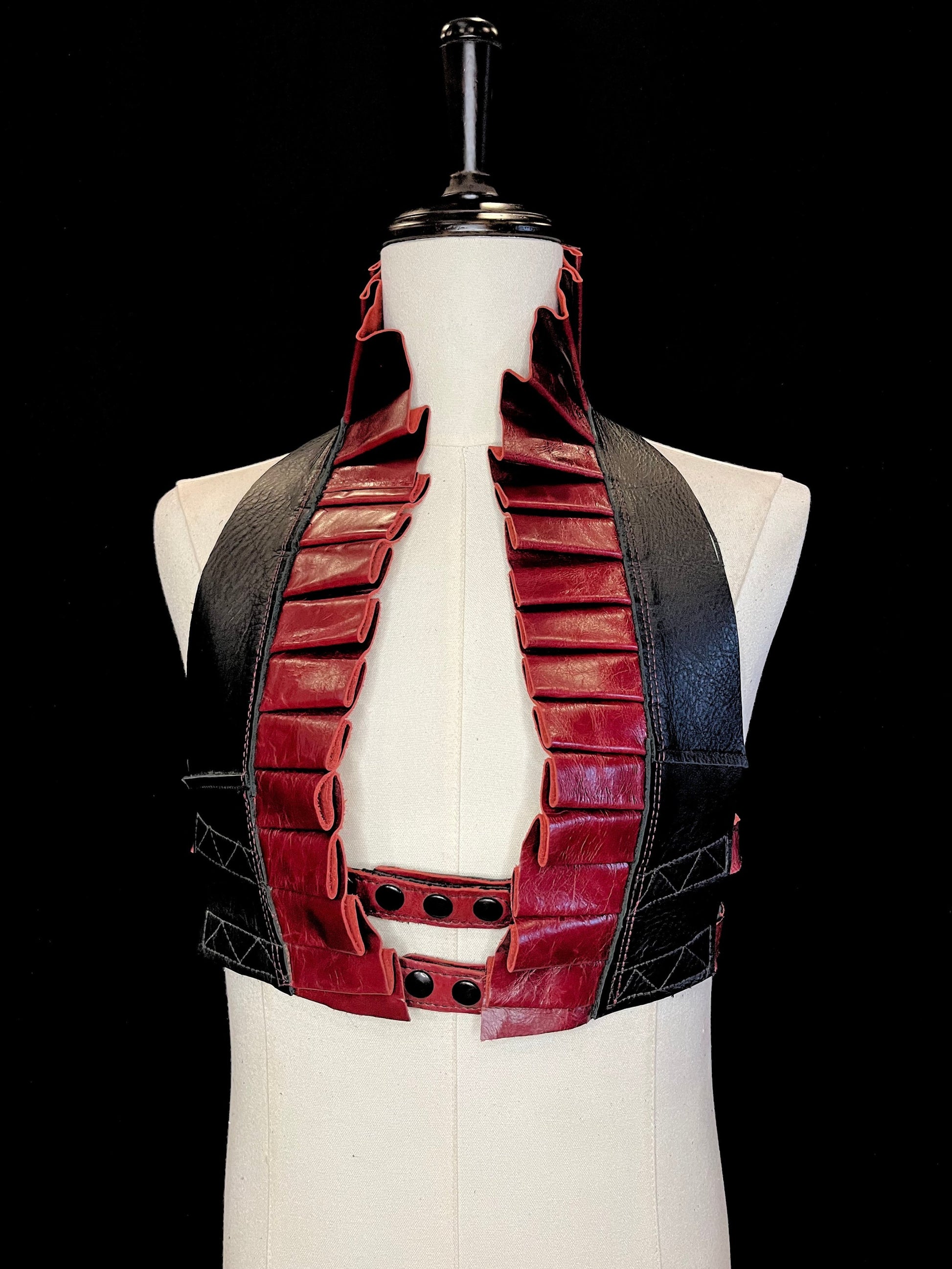 Cabernet oxblood red leather ruff with a black leather neck and black hardware on an ivory non-gender mannequin against a black background