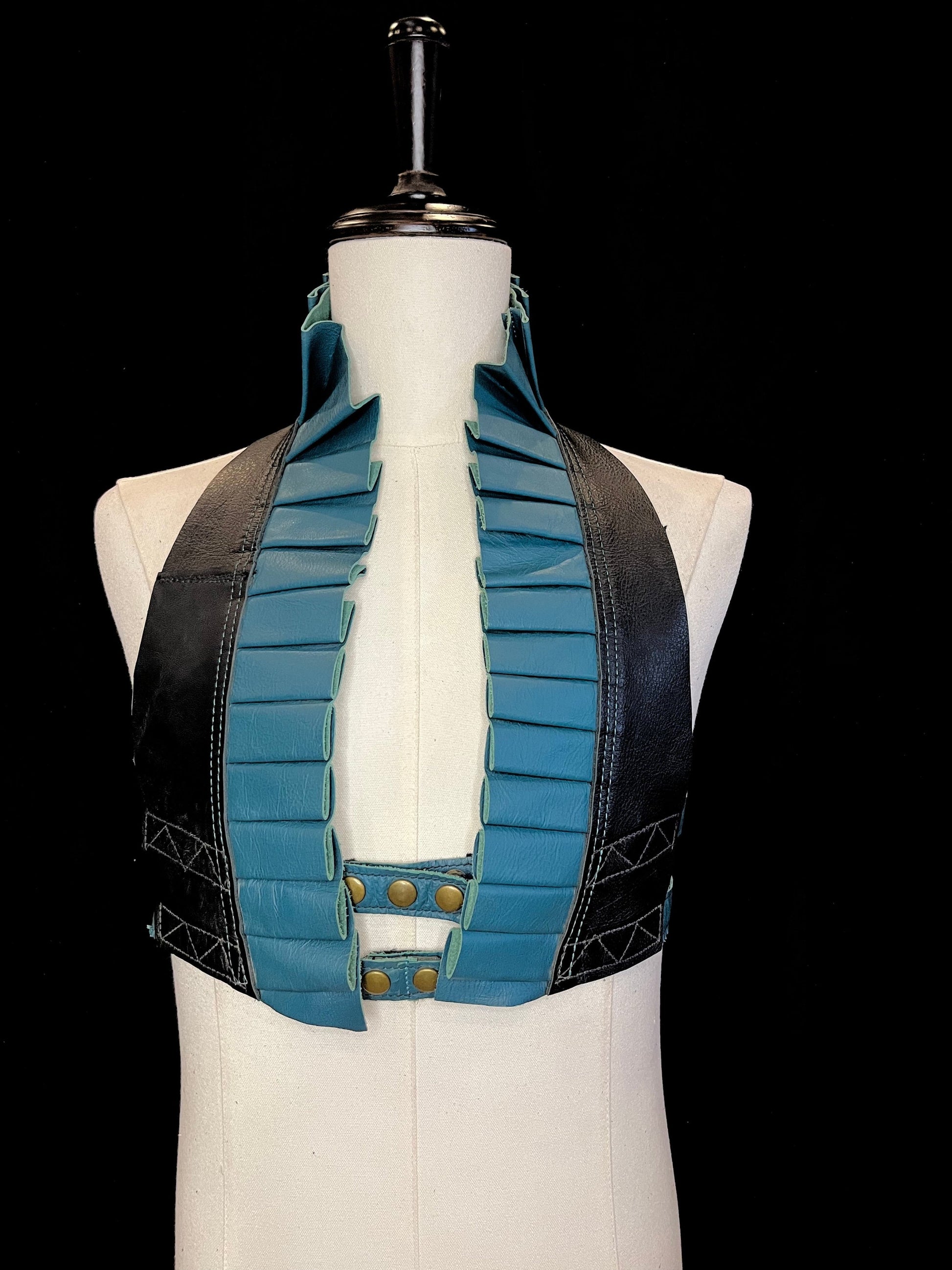 teal leather ruff with a black leather neck and antique brass hardware on an ivory non-gender mannequin against a black background