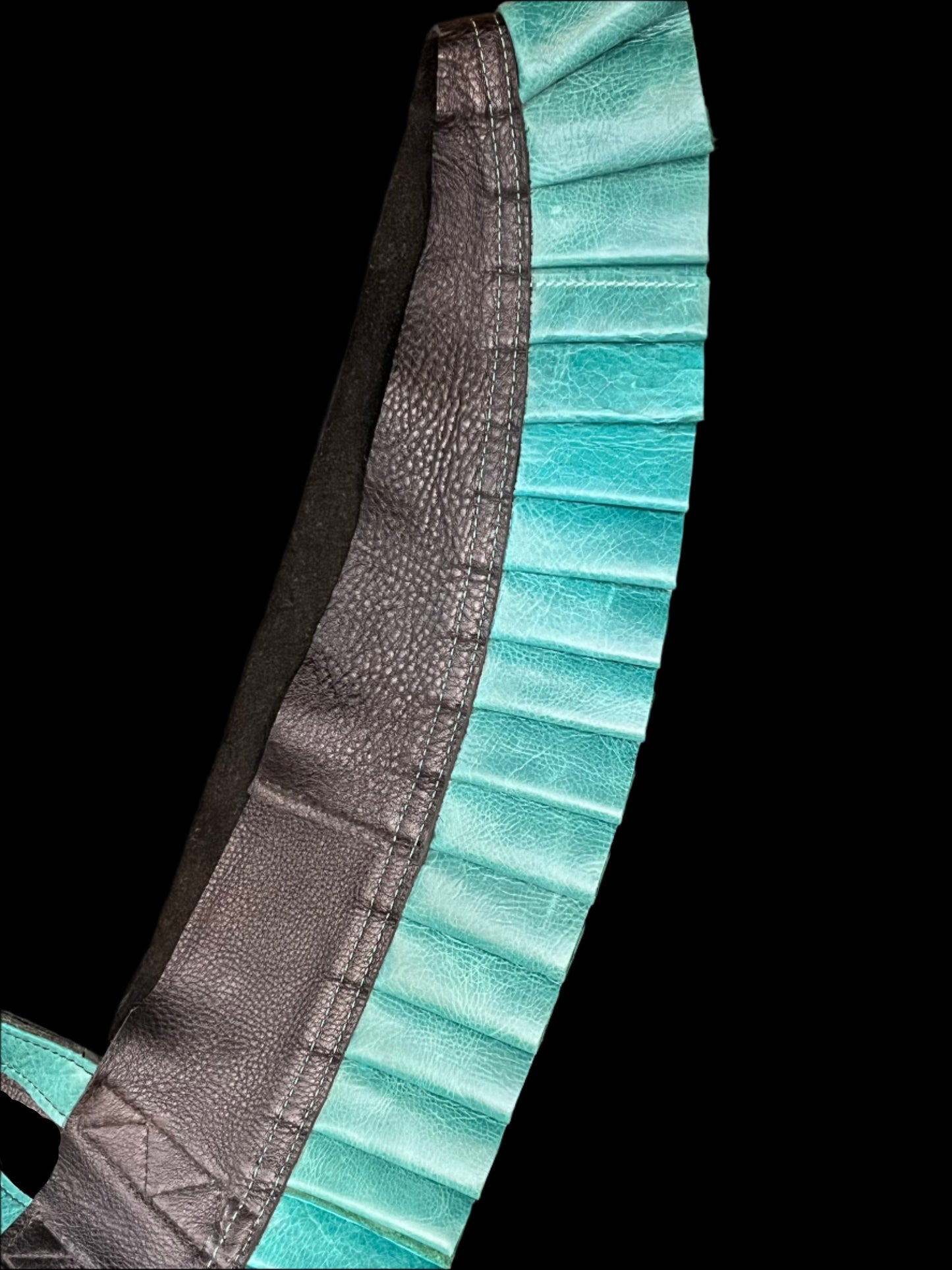 Turquoise leather ruff with a black leather neck on its side on a black background