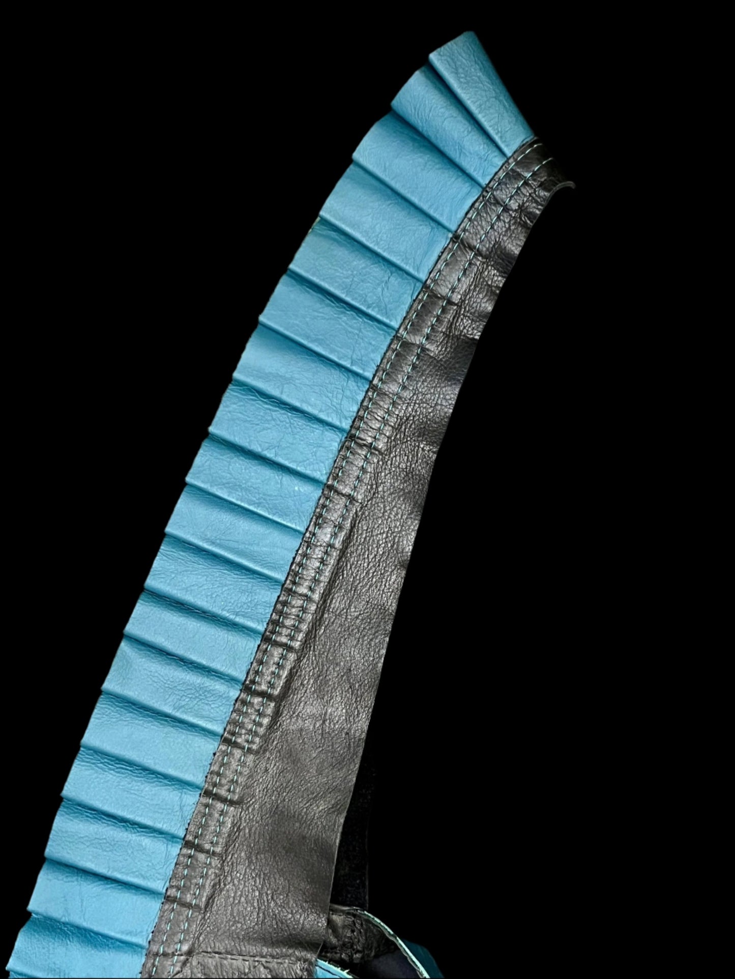 teal leather ruff with a black leather neck on its side on a black background