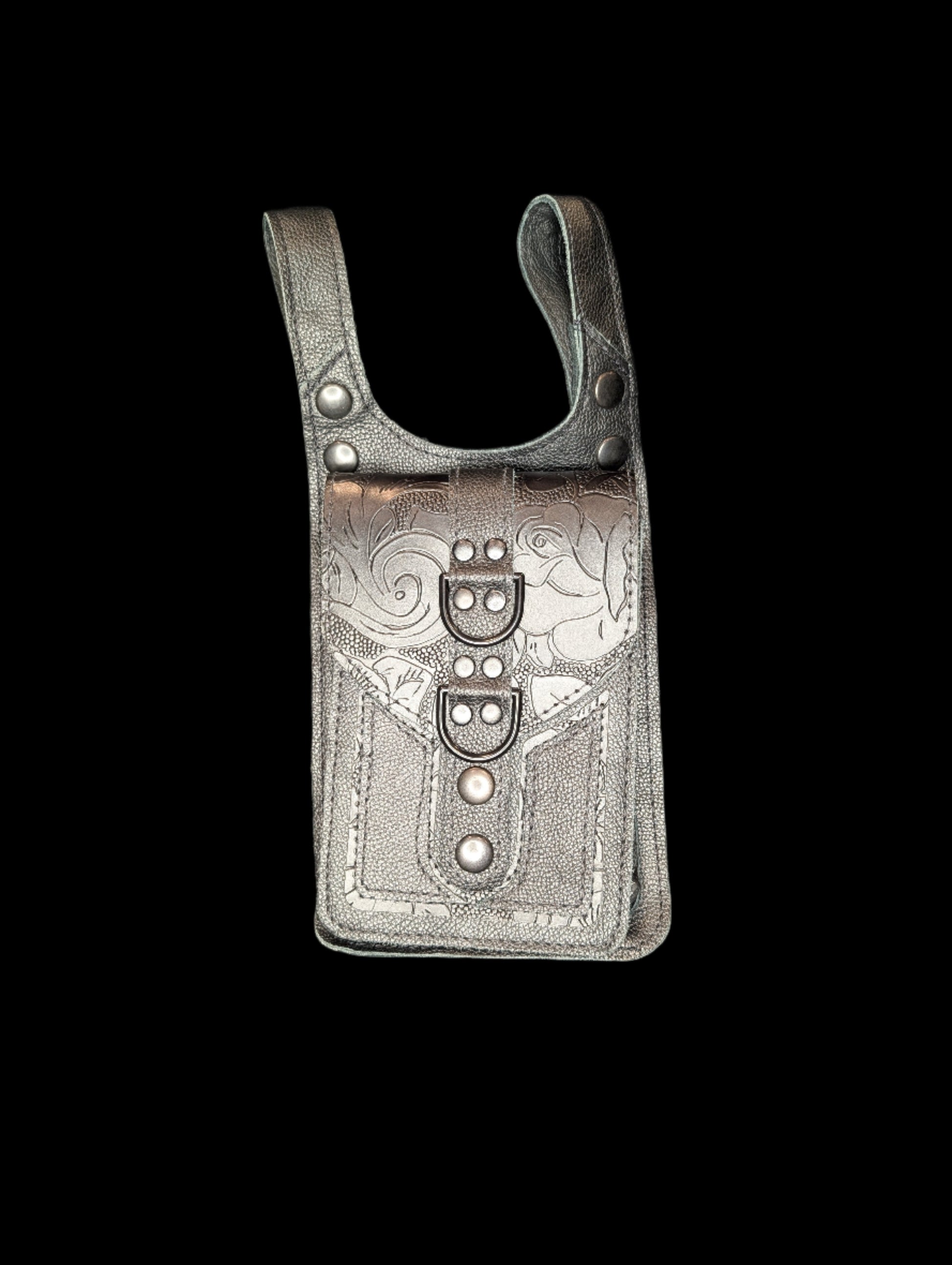 A thigh bag with one large pocket. Base is made with a black leather. Pocket base is made with a black leather with floral black and smooth black leather accents. The pocket flap is made with a black floral leather with a black strip. Includes black stitching and black hardware.