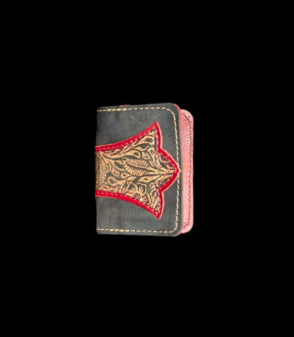 A wallet folded in half showing a base color of black leather with a layered trident accent in red and bronze floral leather with red and bronze stitching.