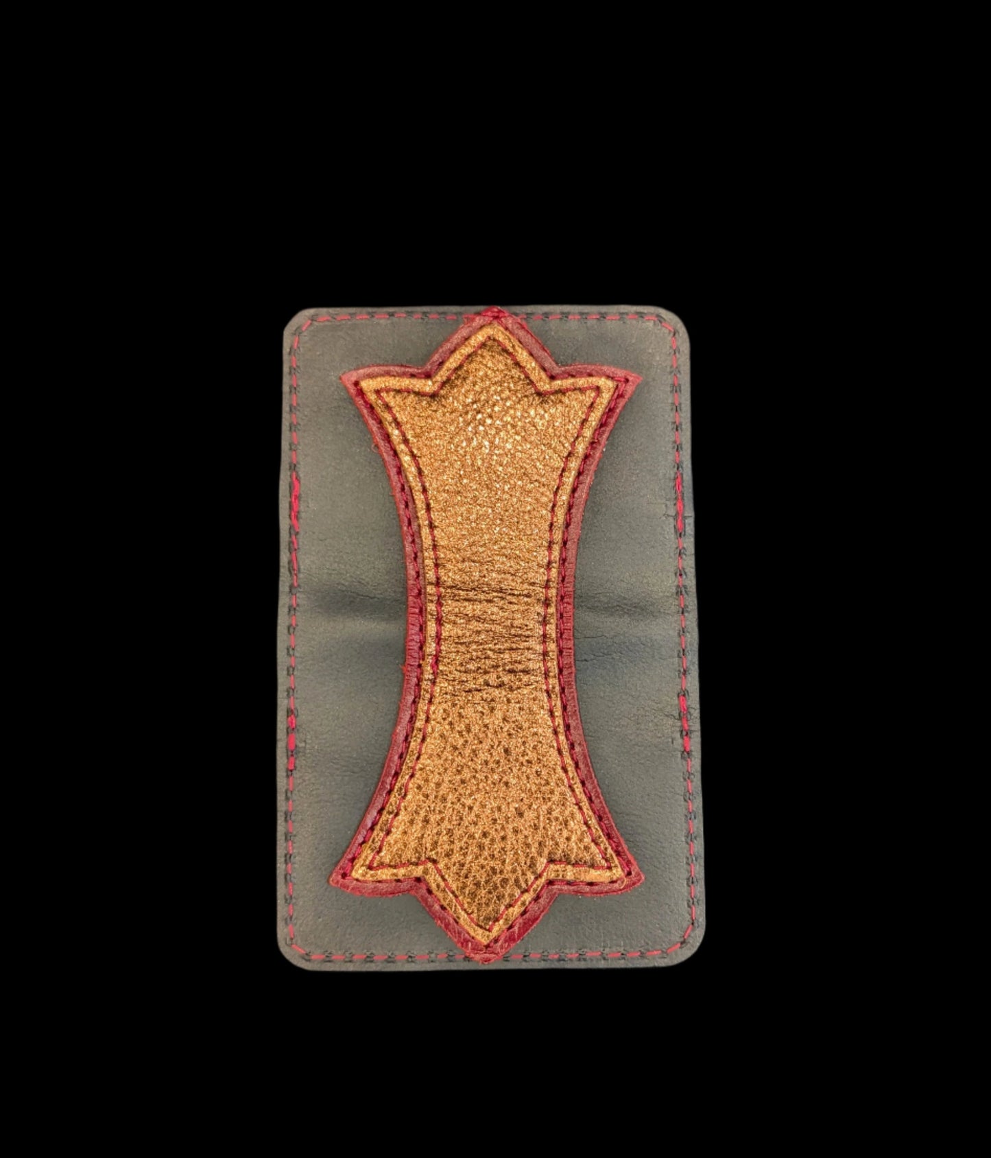 A photo of the outside of a wallet laid flat showing a base color of black leather with a layered trident accent of red leather and bronze leather and red stitching. 