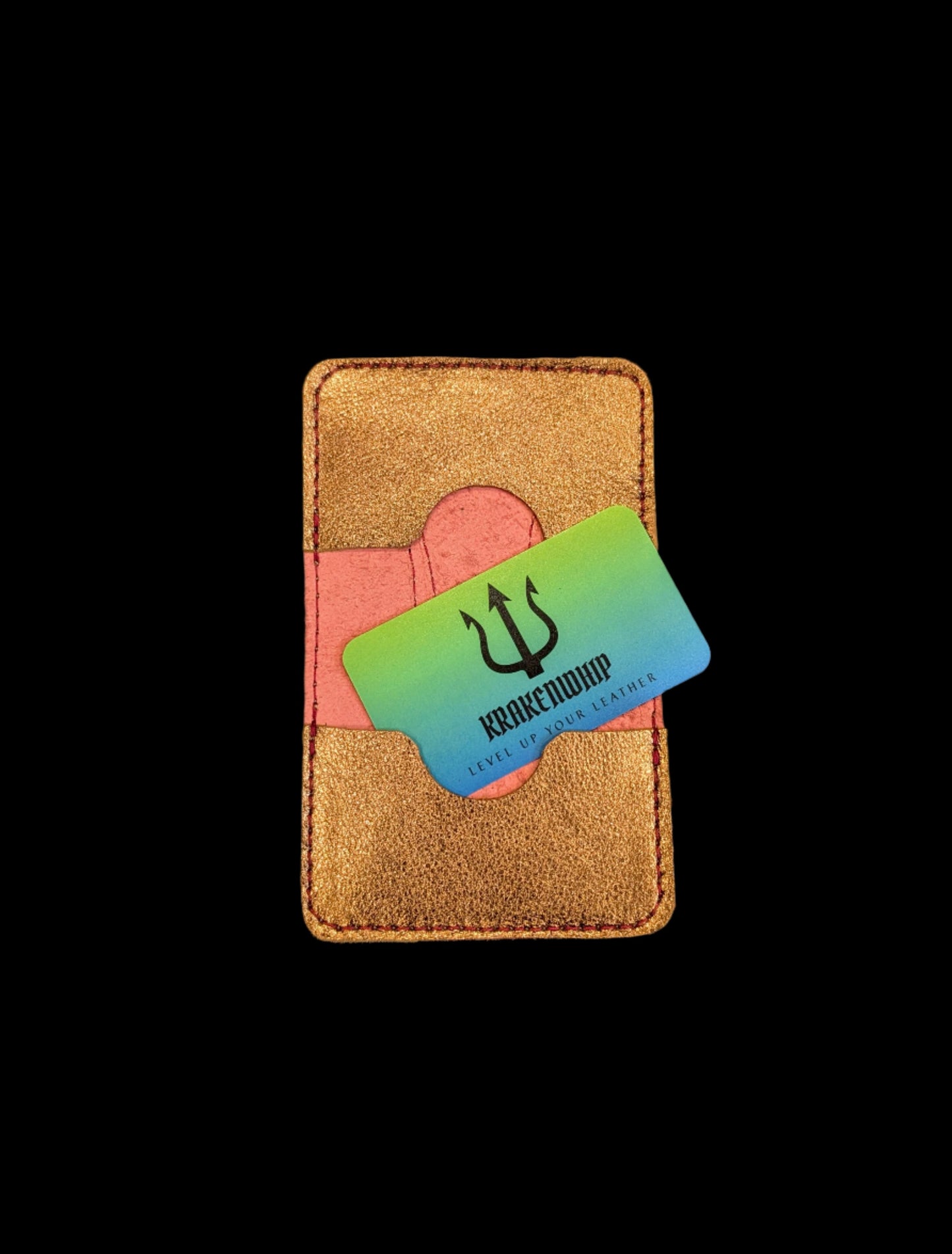A wallet spread open showing a base color of red leather with two card pockets in bronze leather with red stitching. A krakenwhip business card is sticking out of one of the pockets.