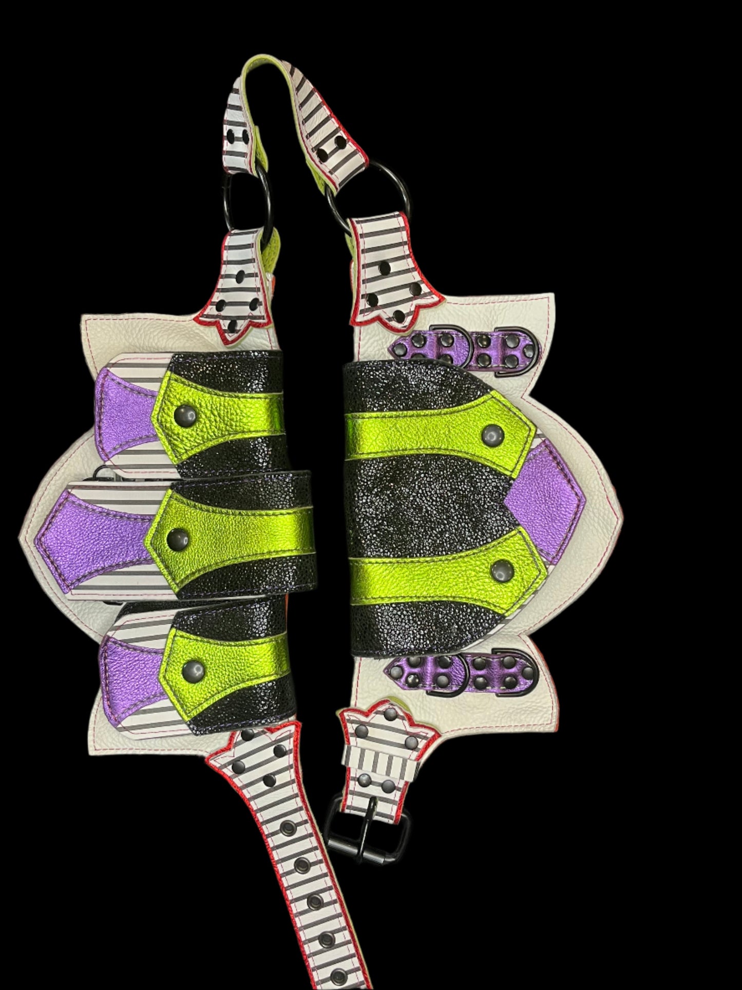 Leather regal belt laid flat showing black and white striped, metallic lime, metallic purple, and metallic red leather and black hardware on a black background