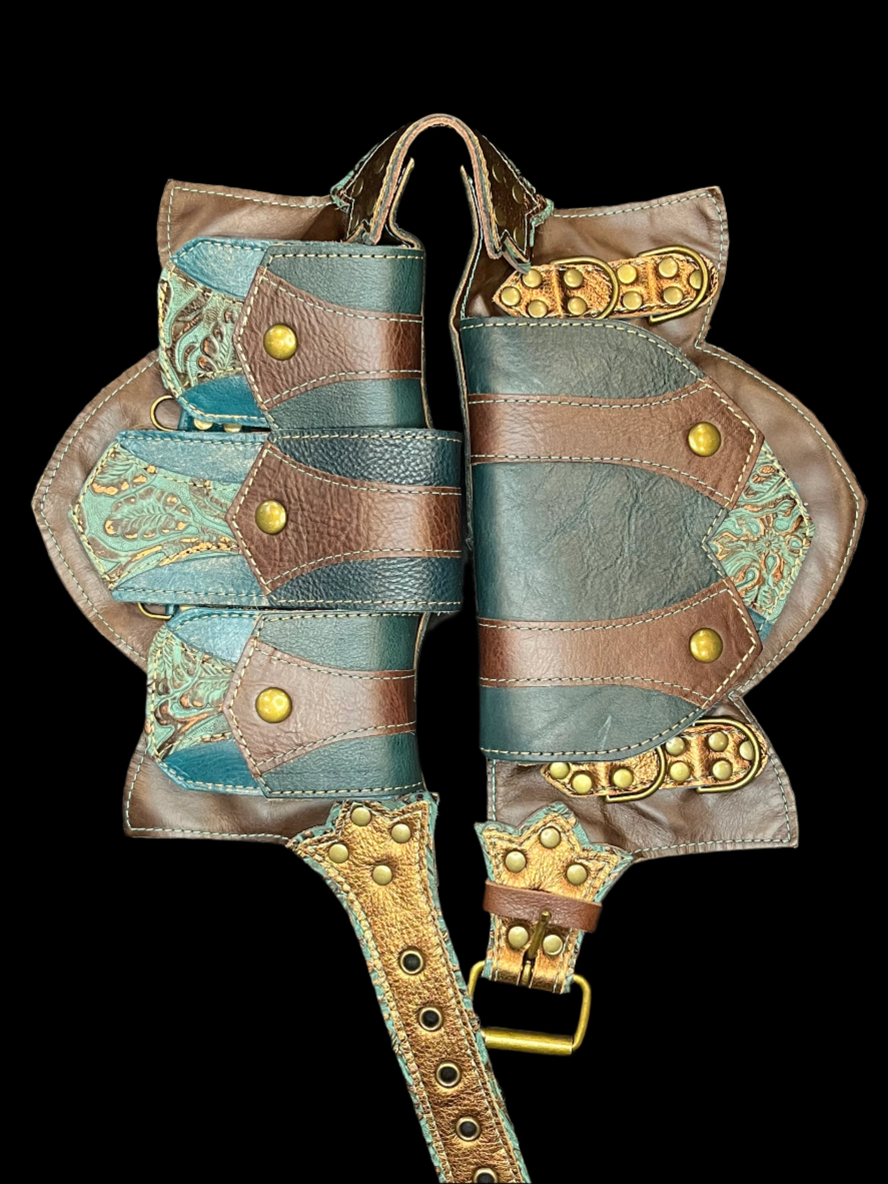 Tortuga belt in teal, brown, and bronze leathers laid flat on a black background