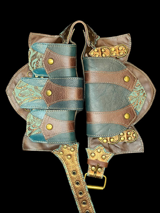 Tortuga belt in teal, brown, and bronze leathers laid flat on a black background