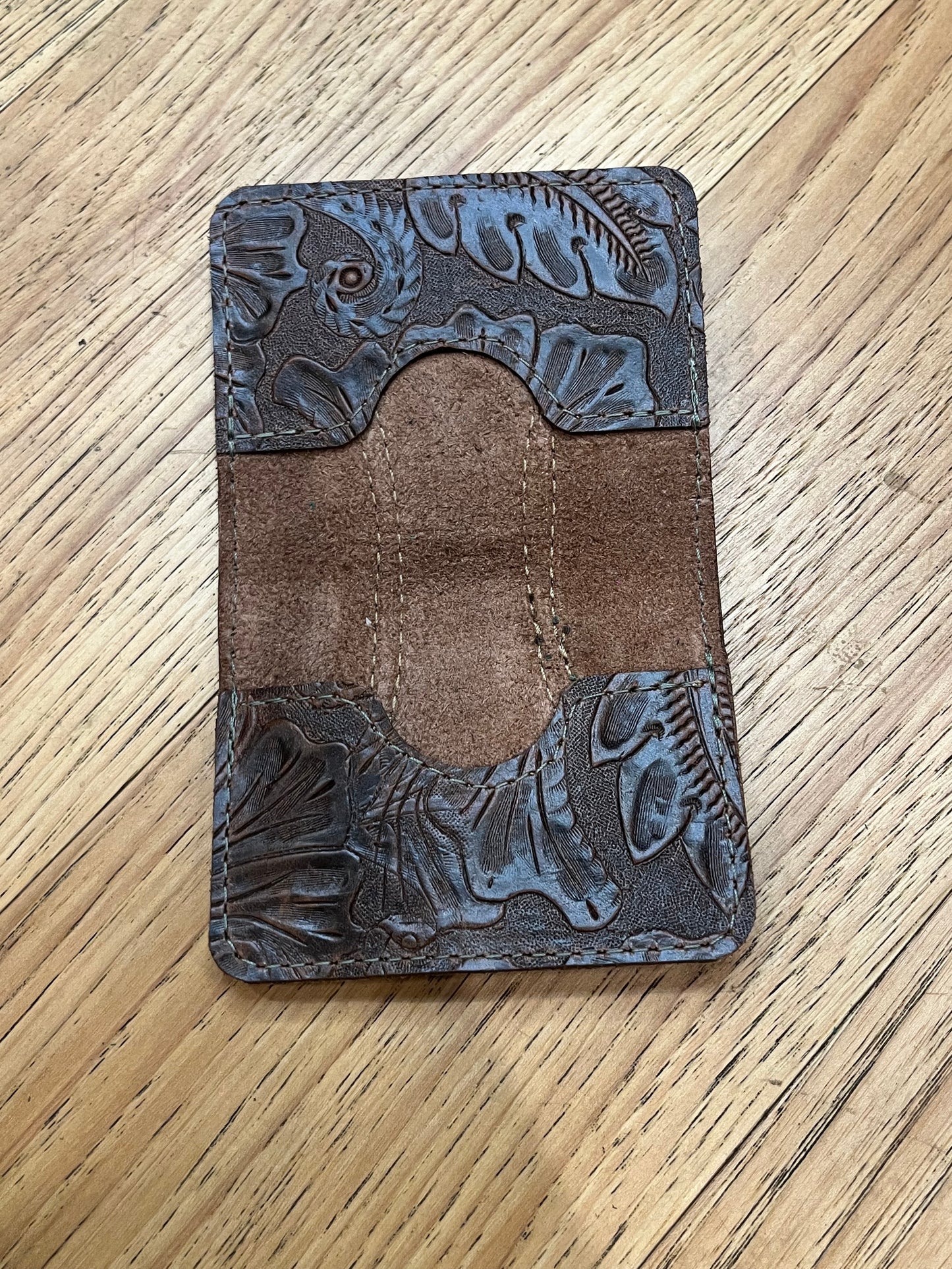A wallet spread open showing a base color of brown leather with two card pockets in brown floral leather with brown stitching. 
