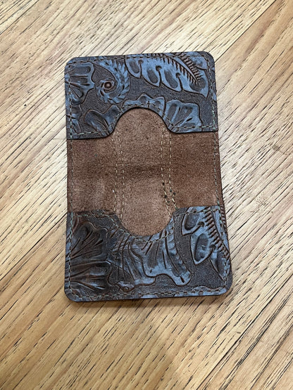 A wallet spread open showing a base color of brown leather with two card pockets in brown floral leather with brown stitching. 