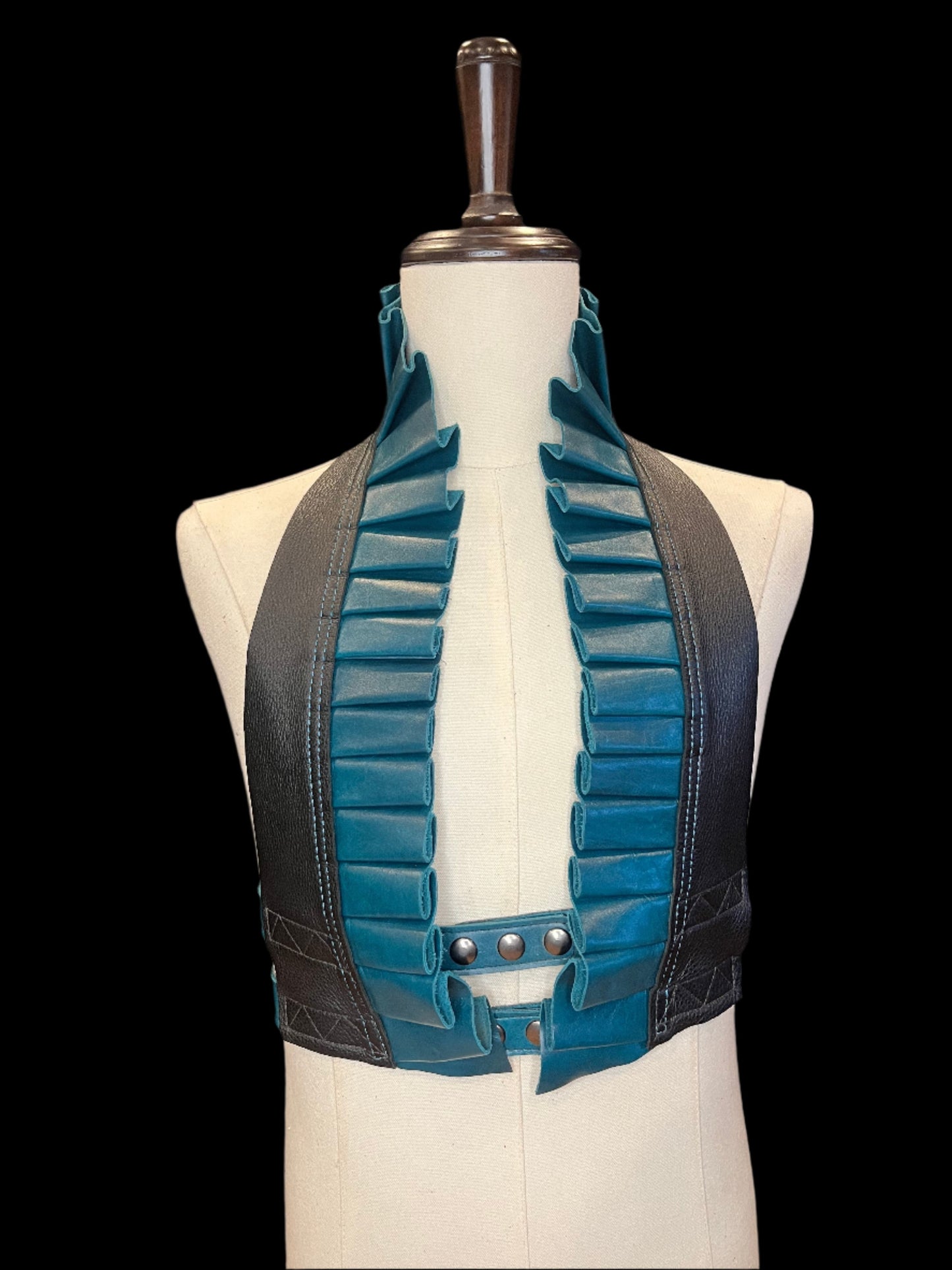 Black and turquoise leather ruff top with pewter hardware on an ivory mannequin against a black background